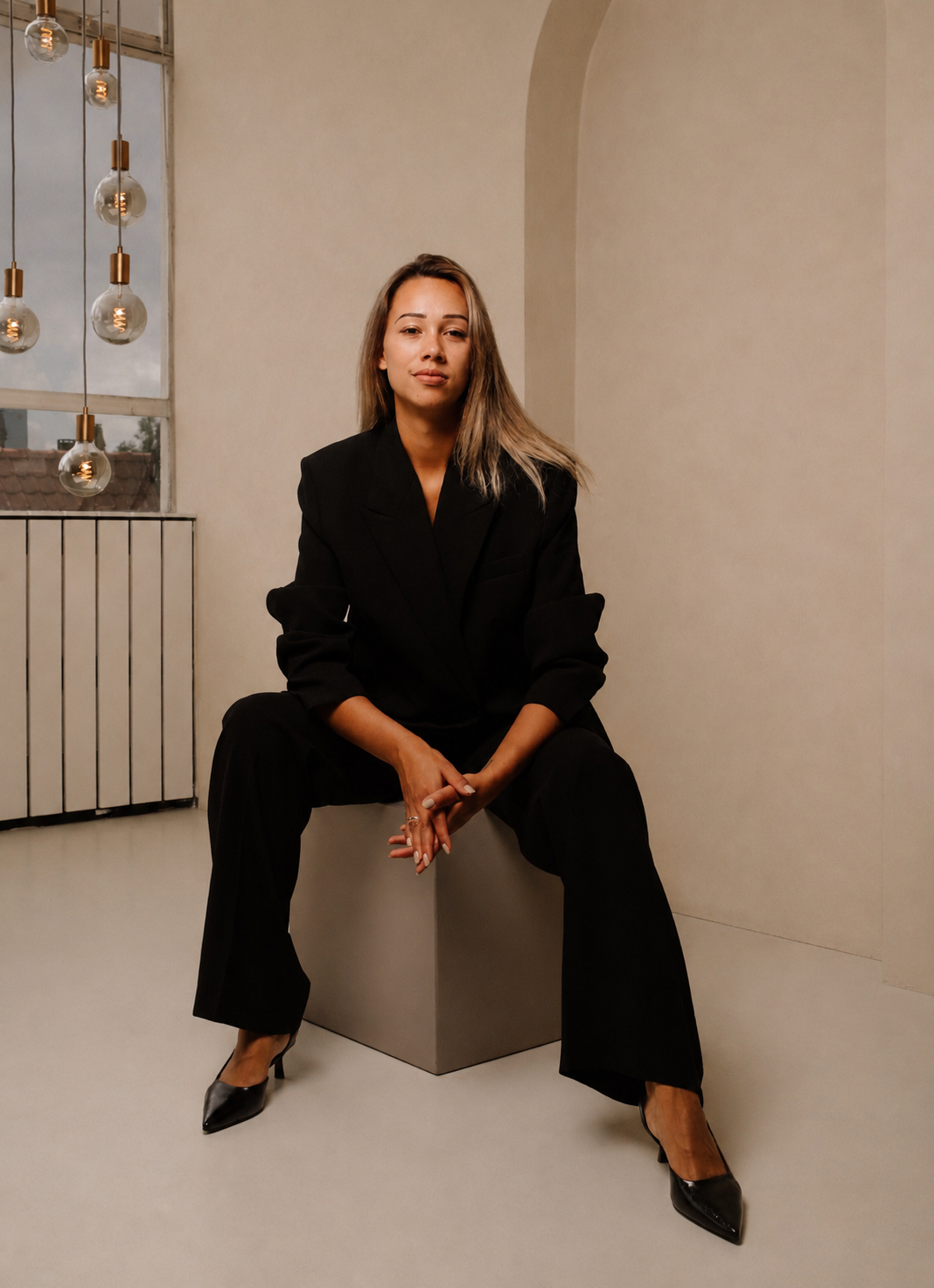 Portret van Michelle Daisy zittend op een blok in een lichte ruimte.