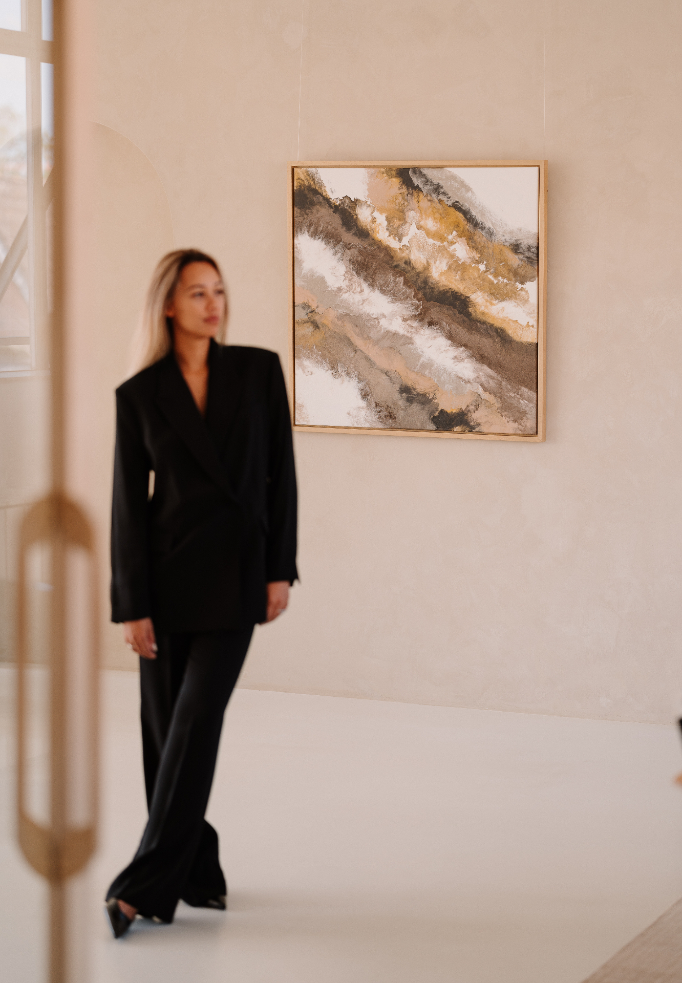 Michelle Daisy loopt langs een groot schilderij in haar studio.