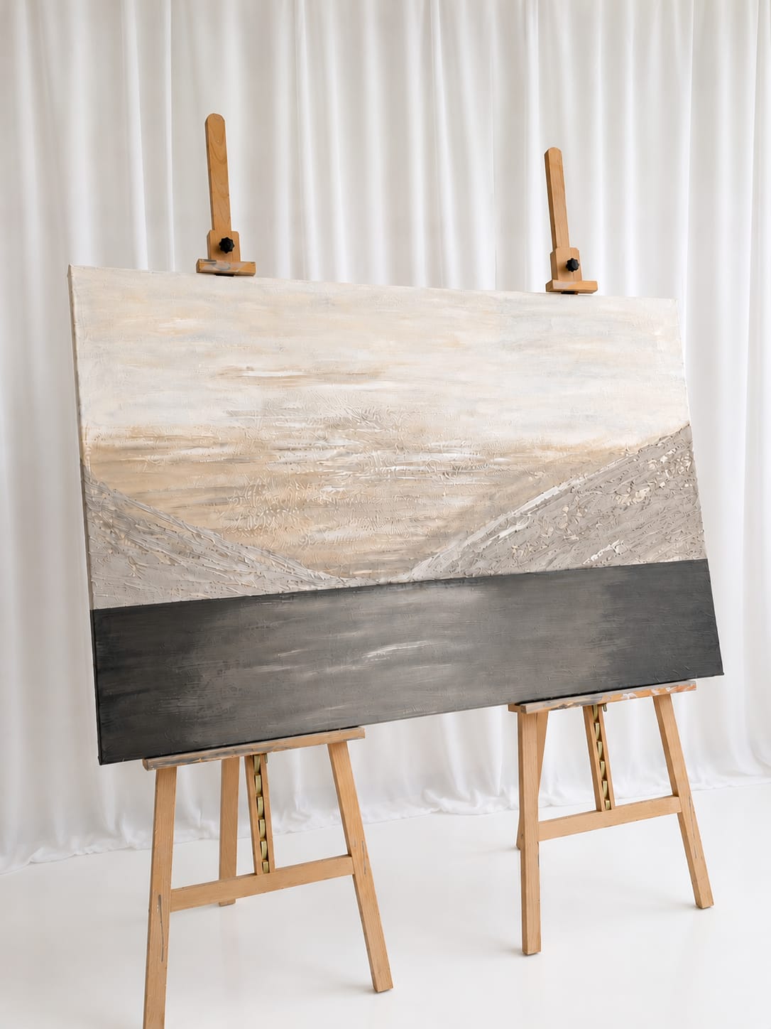 Groot landschapsschilderij in aardetinten op twee schildersezels in het atelier.